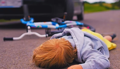 An image of a child who's been hit by a car while riding a bicycle.