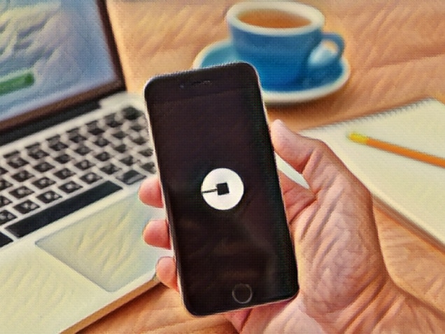 man holding iphone6 showing uber app with laptop on the background