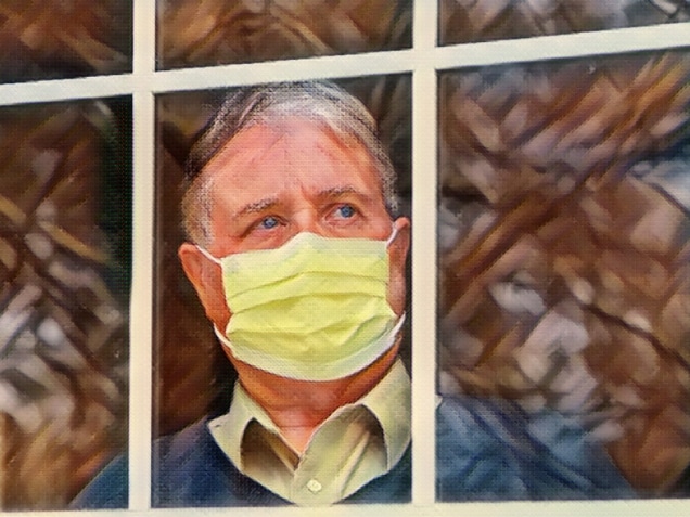 Man wearing mask inside staring out the window