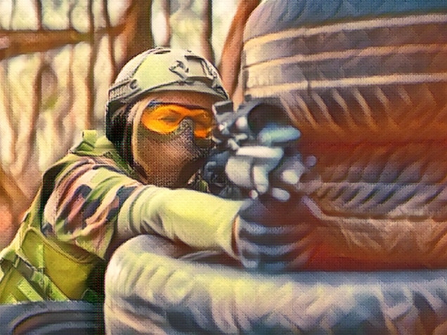 man hiding behind tyres while playing airsoft