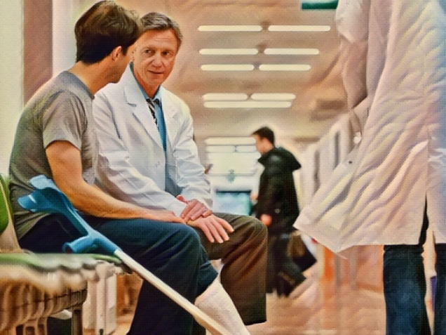 Mature man with broken leg, cast and crutches consulting a senior doctor. Shot in hospital corridor.