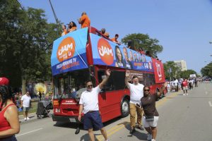 Ankin Law Office employees waving and smiling beside a big red bus at the Bud Billiken Parade