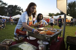 A woman wearing the winning Race Judicata t-shirt design getting food at the buffet table