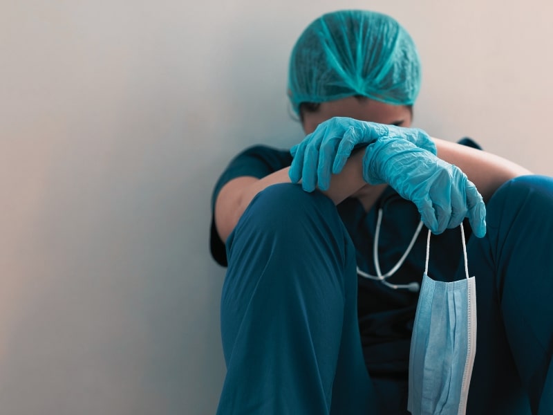 Stressed tired healthcare worker sitting on floor
