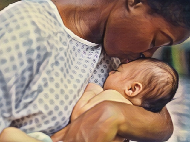 A beautiful young African American mother in a hospital gown gently holds her infant in her arms and smiles down at her. Concept of what is a birth injury