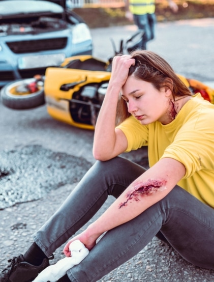 bloody young woman sits on the ground after a motorcycle accident. 1293445785