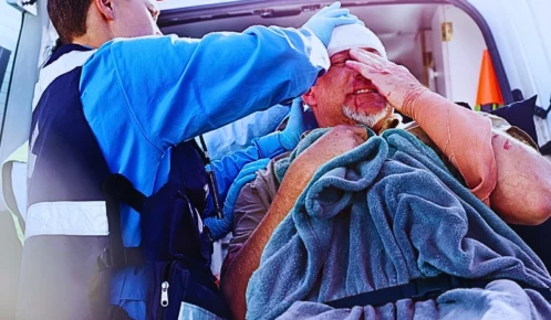 Rescue worker tending to patient at back of ambulance. pain and suffering after a truck accident