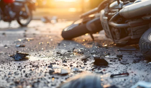 Motorcycle lying on the ground with sunset light on the background.