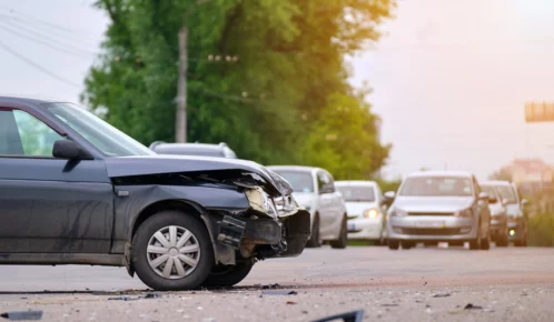 Wrecked black sedan car in the middle of the road.