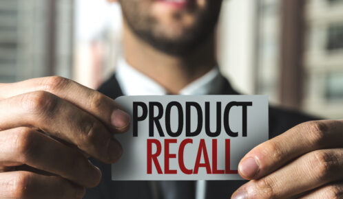 Man in suit holding a piece of paper with Product Recall printed in black and red.