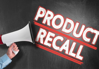 Hand holding megaphone or bullhorn against blackboard with text PRODUCT RECALL.