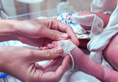 A nurse applying an oximeter on a newborn infant. Baby Formula Linked to Necrotizing Enterocolitis