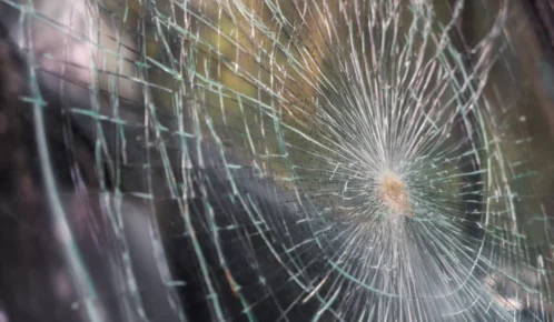 Close-up image of a shattered glass surface with a central impact point and radiating cracks.