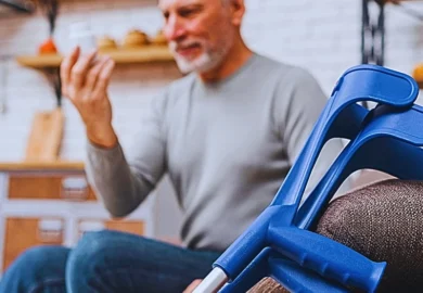 Adult man in pain sitting on the couch with his blue crutches on the side. How Courts in Illinois Value Personal Injury Cases