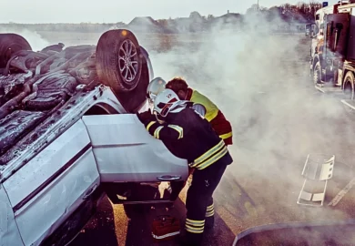 On the car crash traffic accident scene: rescue team of firefighters pull victim out the roll over vehicle.