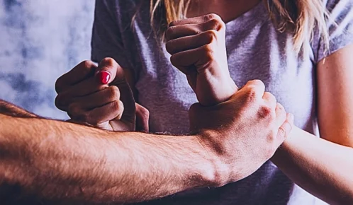 Abusive husband holding his wife's wrists. Criminal Charges and Civil Claims for Sexual Assault