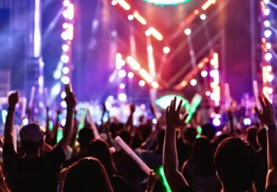 Crowd of hands up concert stage lights and people fan audience silhouette raising hands. Liability for Assaults at Concerts