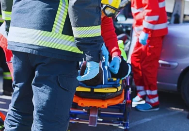 Emergency responders attending to a patient on a stretcher outdoors on a street.