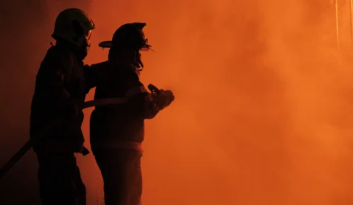 Firefighter spraying water in burning apartment.