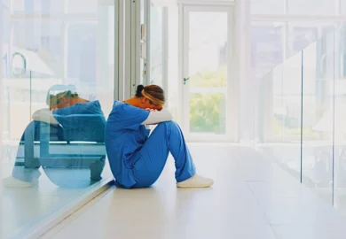 Exhausted healthcare worker sitting on a hospital floor. Staffing Shortages Lead to Serious Injuries