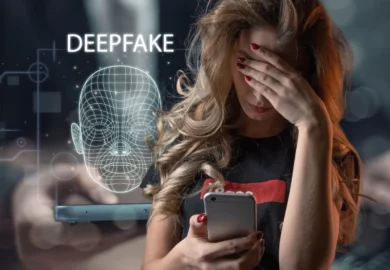 Distressed woman covers eyes near phone with deepfake graphic.