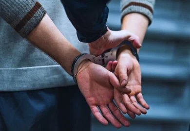 A suspect with handcuff being held by a police.
