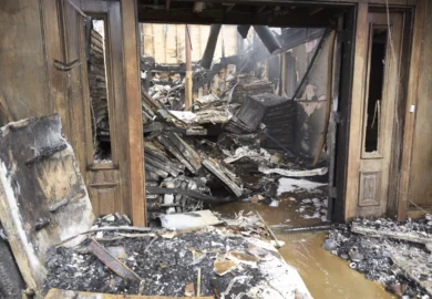 Severe fire damage inside a building with charred debris.