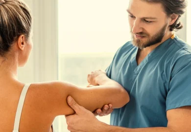 Male physical therapist examining a female patient's injured arm. Massage Therapist Sexual Abuse