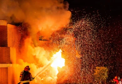 Firefighter aiming the water hose to the fire.