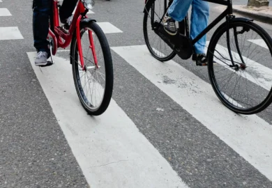 Two cyclists riding bikes across a white painted crosswalk.