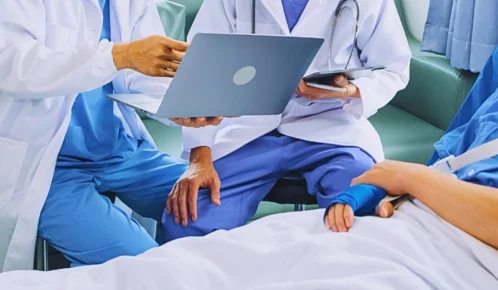 Two doctors showing a laptop to a hospital patient. doctor's notes hurt your car accident claim