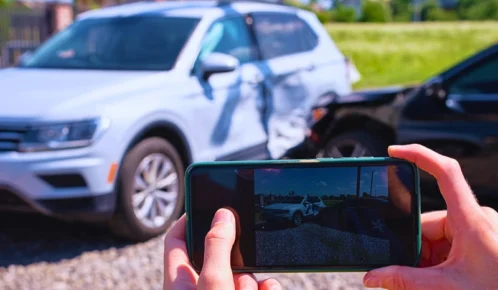 Person taking a smartphone photo of a car accident. evidence conflicts after a Chicago car accident
