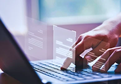 Hands typing on a laptop with digital document.