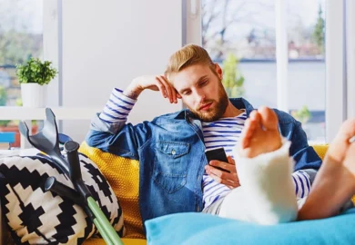 A man with a leg cast rests on a couch. after a personal injury lawsuit is filed