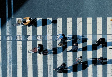 Aerial view of pedestrians and cyclists crossing a striped crosswalk.