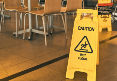 A yellow "wet floor" caution sign in a commercial space.